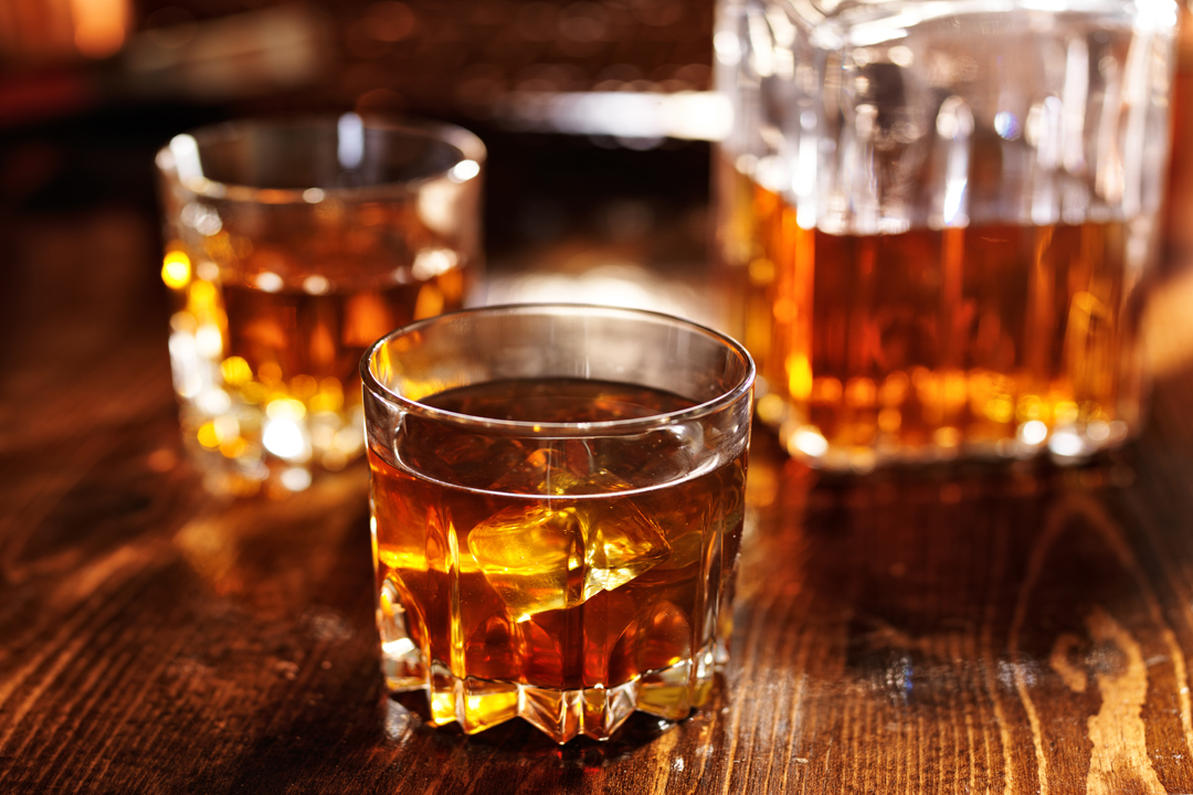 whiskey in glass with decanter in background